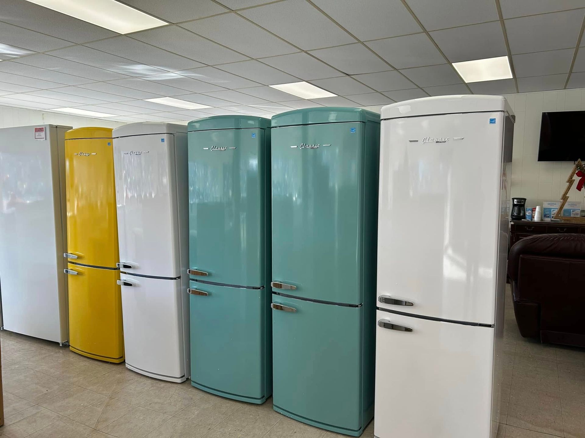 Row of colorful retro refrigerators in a showroom under fluorescent lights