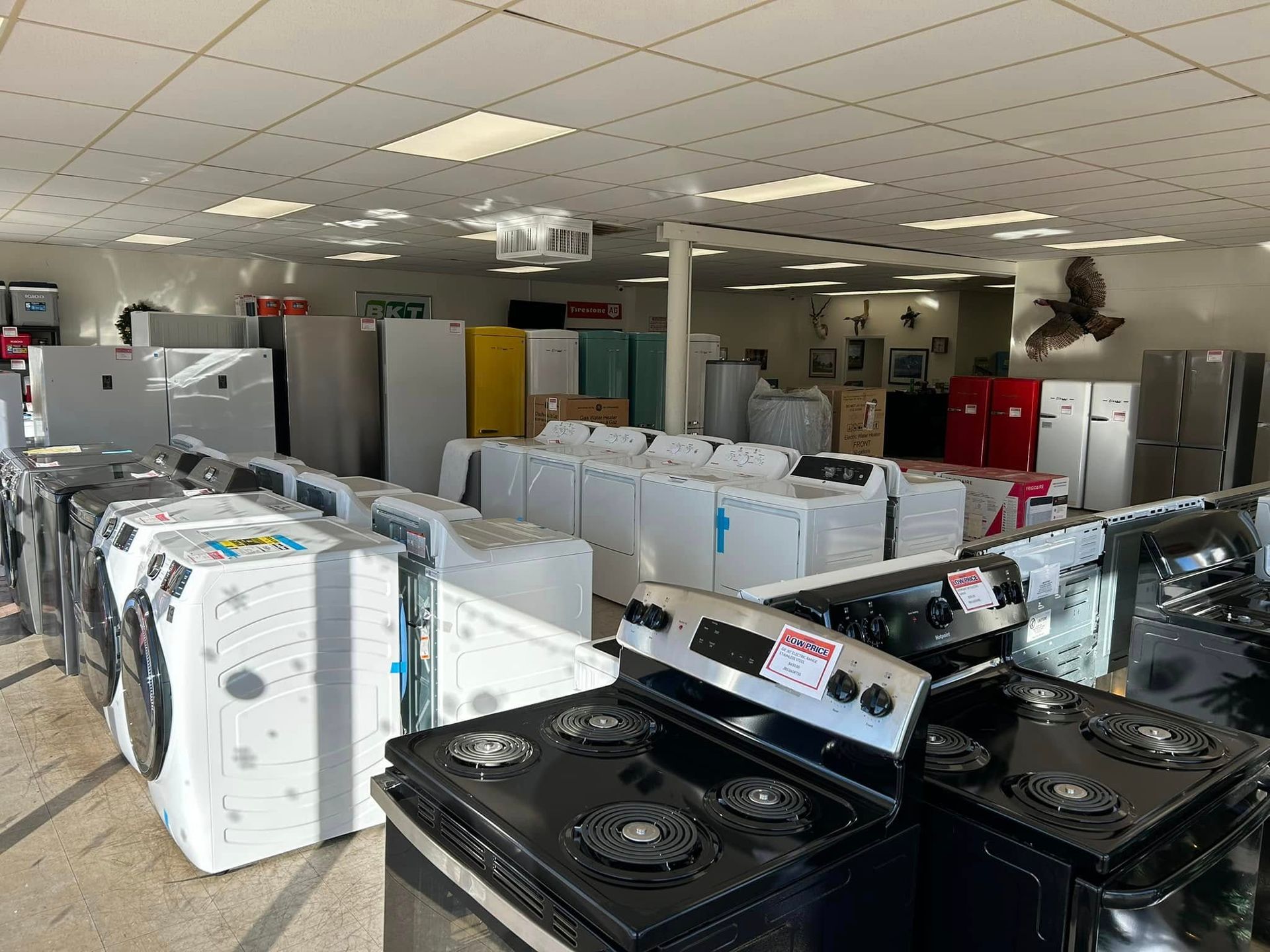 Appliance showroom with rows of washers, dryers, and refrigerators under bright ceiling lights
