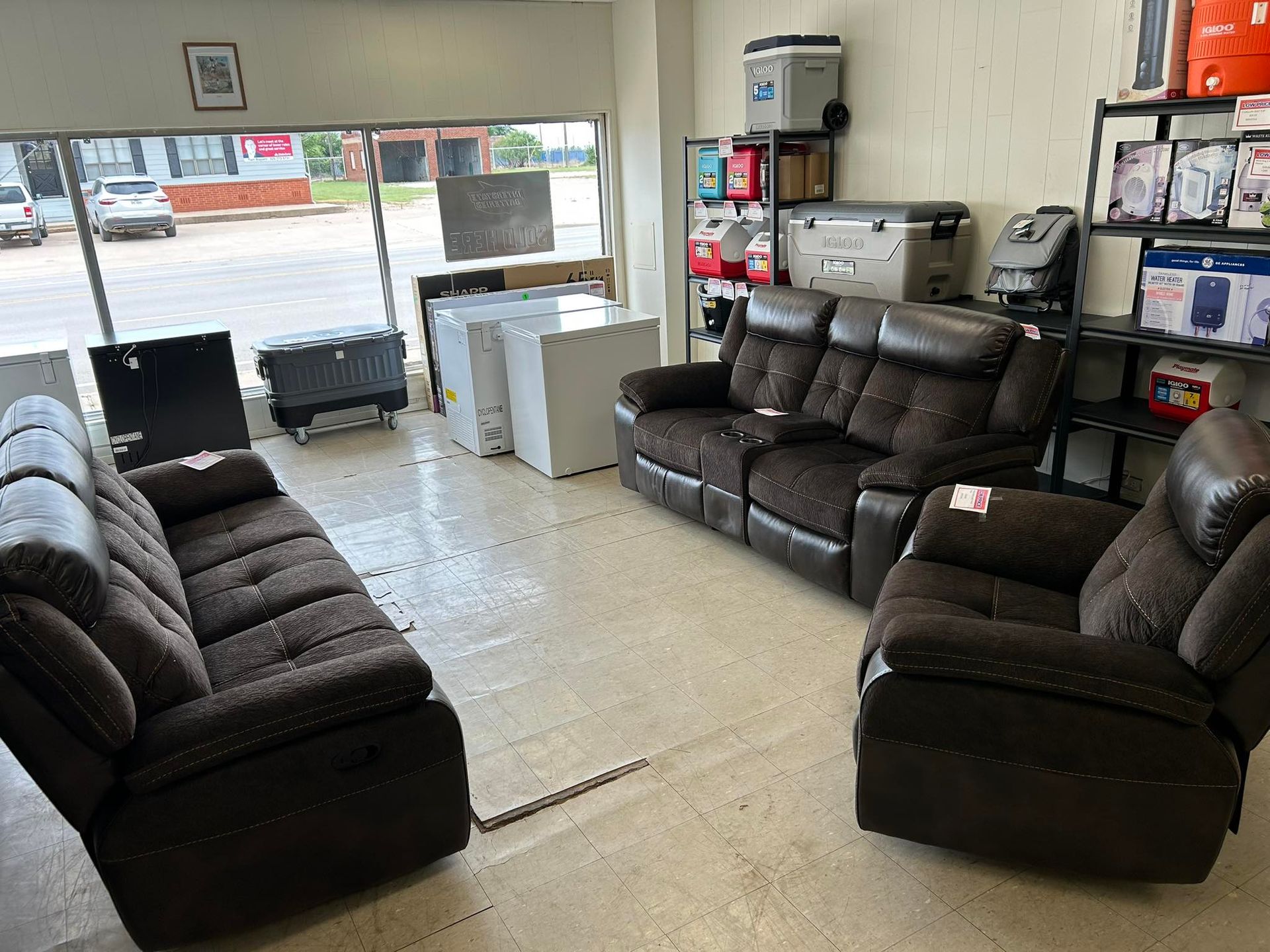 Furniture store showroom with dark brown sofas and recliners arranged around a tiled floor.