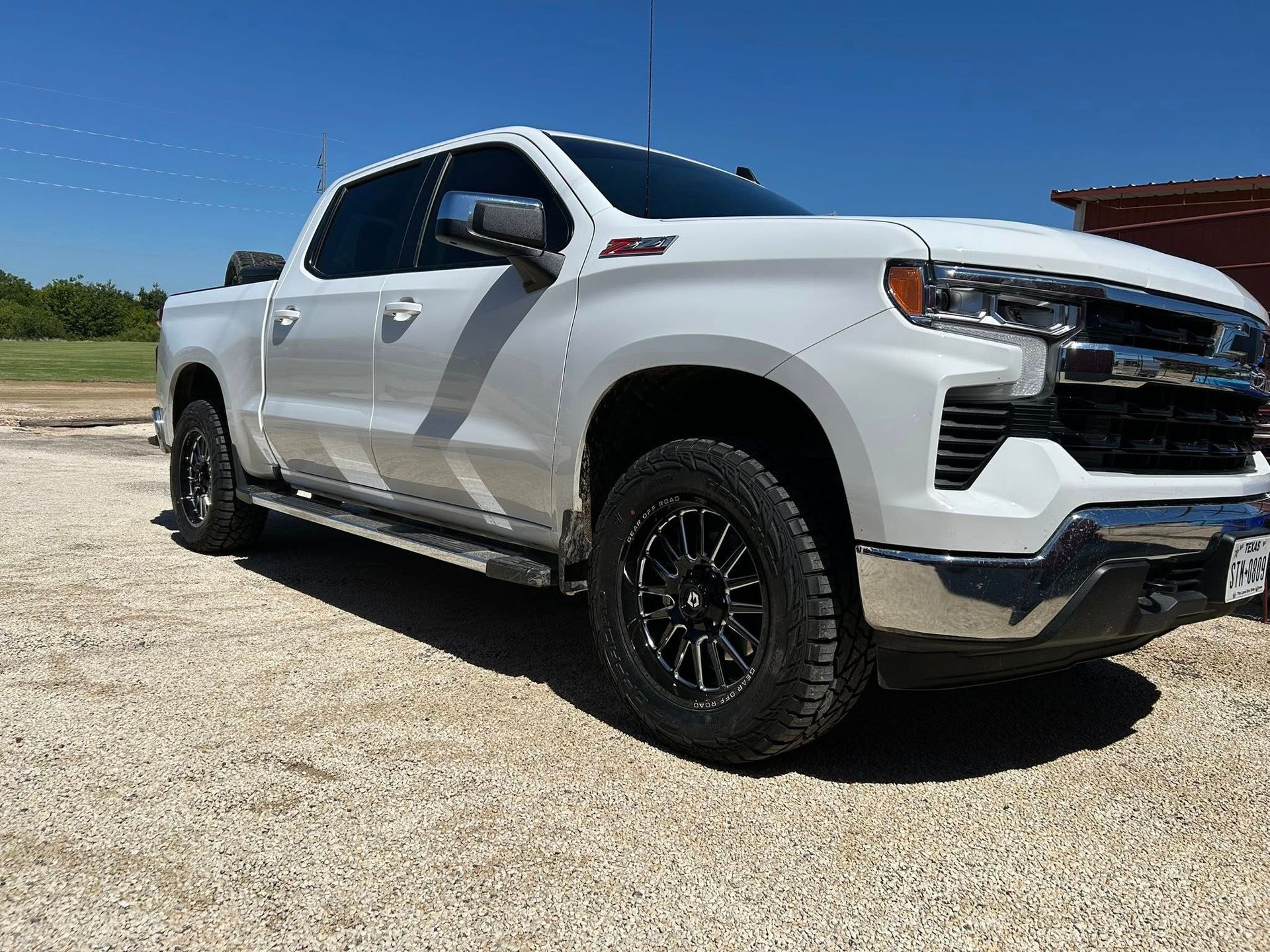 White pickup truck parked on a gravel lot under a clear blue sky.