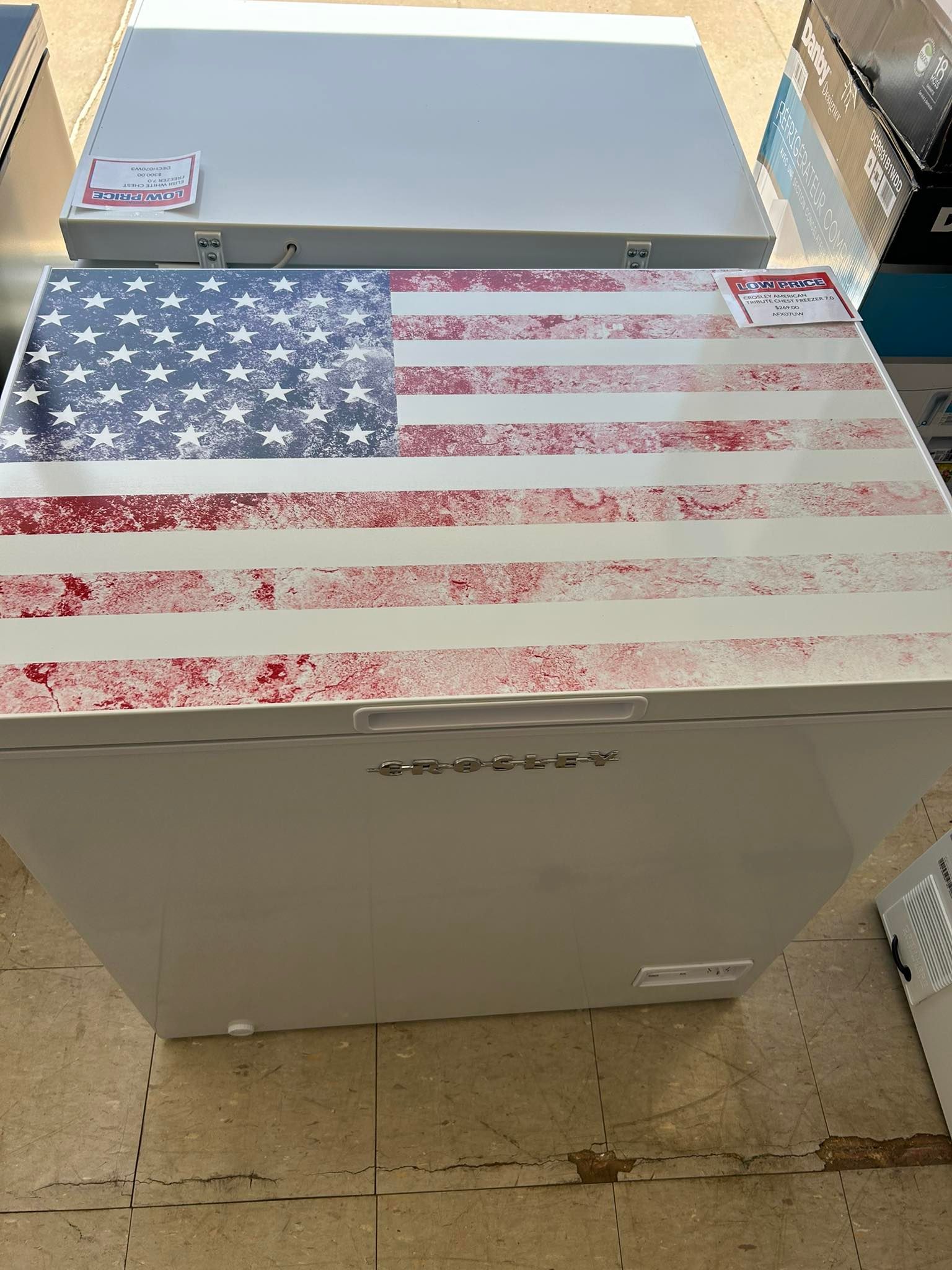 White storage chest with an American flag top, sitting on a concrete floor outdoors.