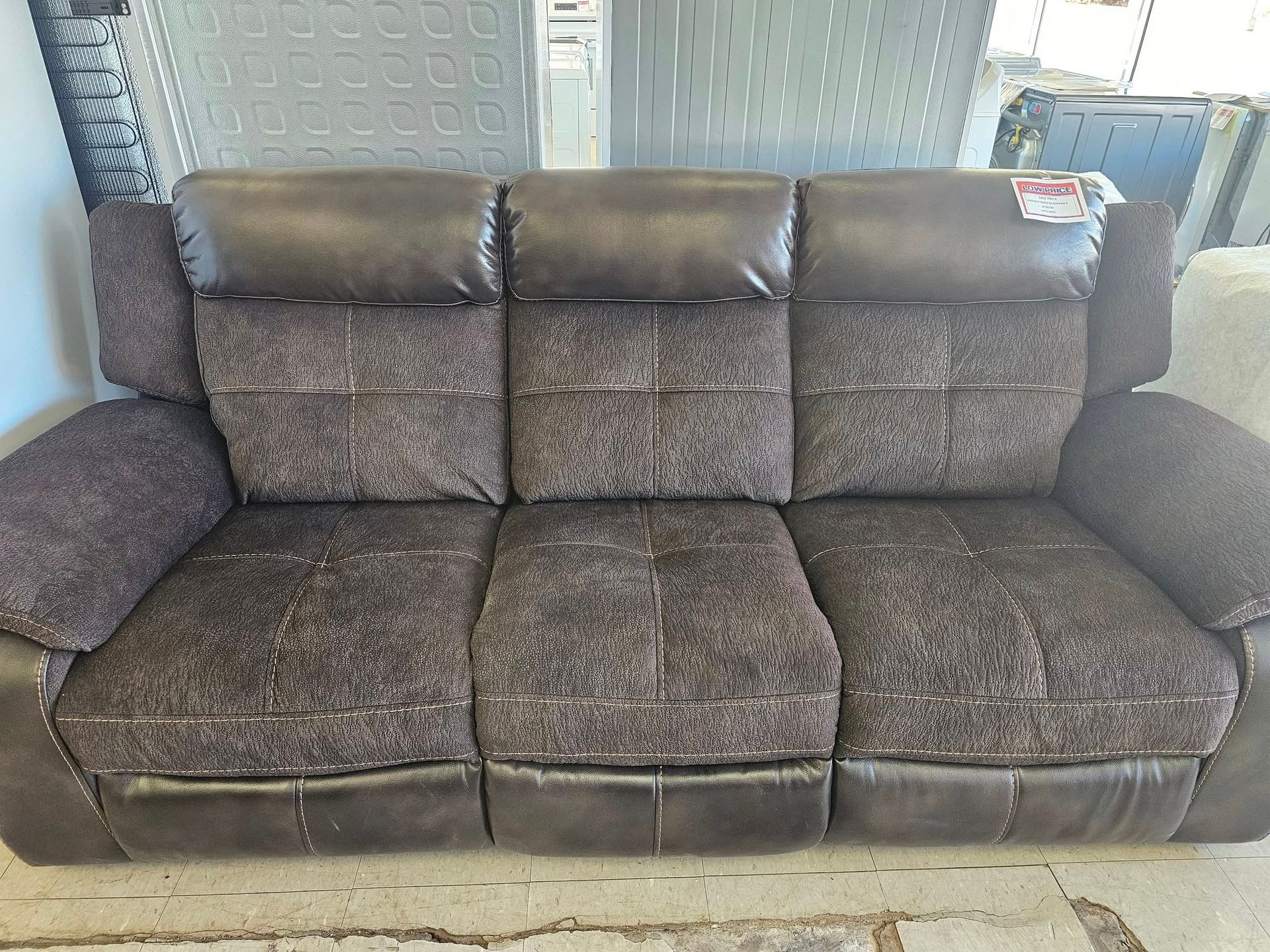 Gray upholstered three-seat sofa with matching center console, shown against a wall.