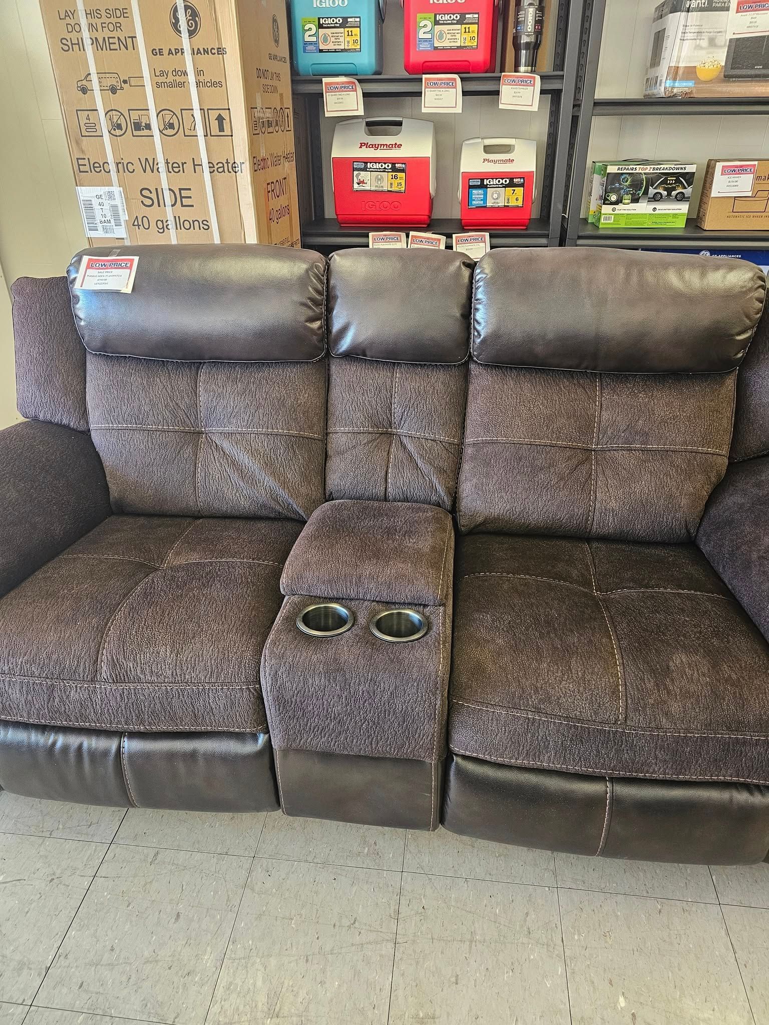 Brown three-seat recliner sofa with cup holders in a furniture store showroom