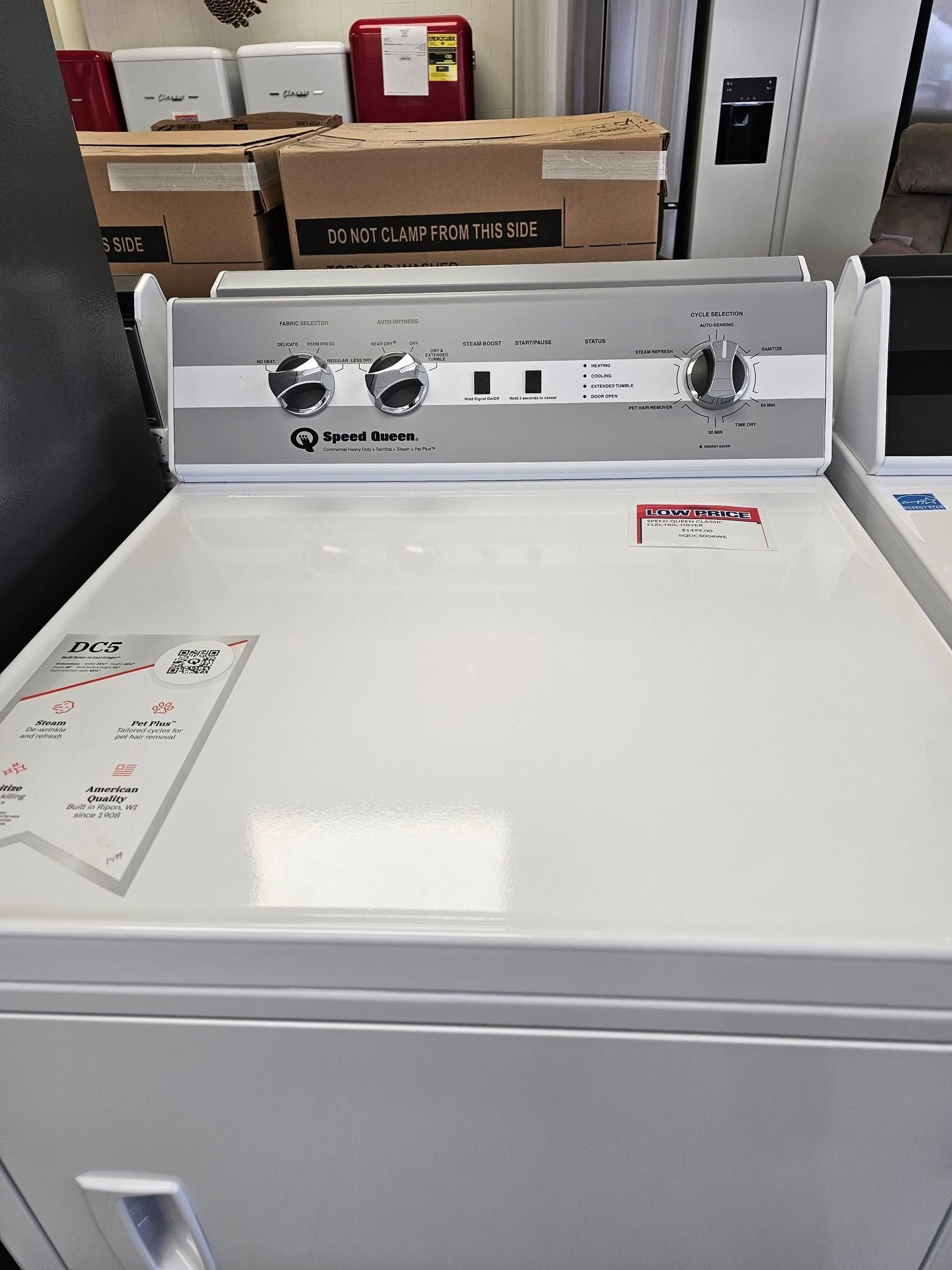 White top-loading washing machine with control panel, shown in a laundry room.