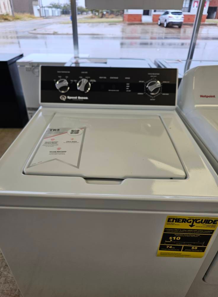 White top-loading washing machine in a laundromat, with a control panel and a price tag.