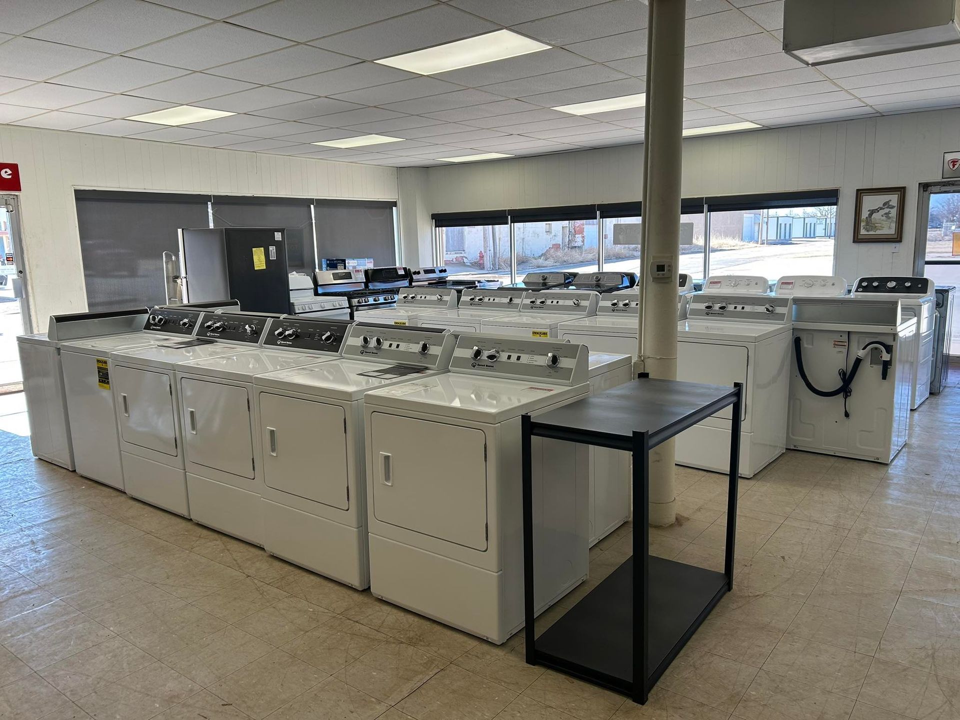 Laundry room with rows of washers and dryers in a bright, tiled utility space