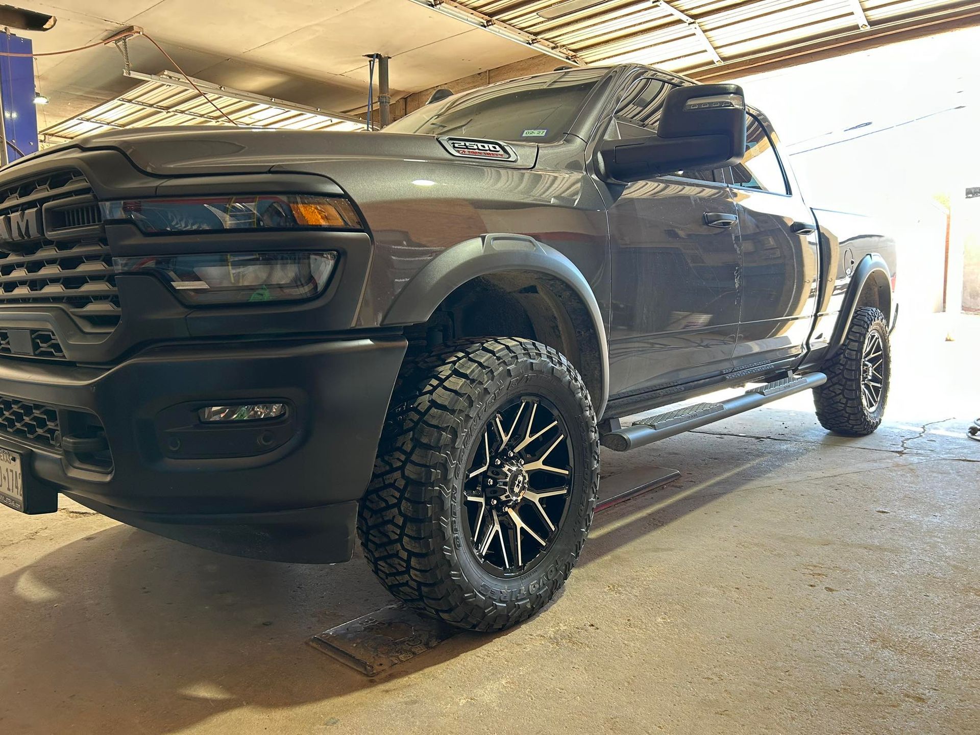 Black RAM pickup truck with off-road tires parked in a garage.