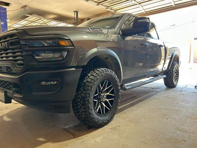 Black RAM pickup truck with off-road tires parked in a garage.