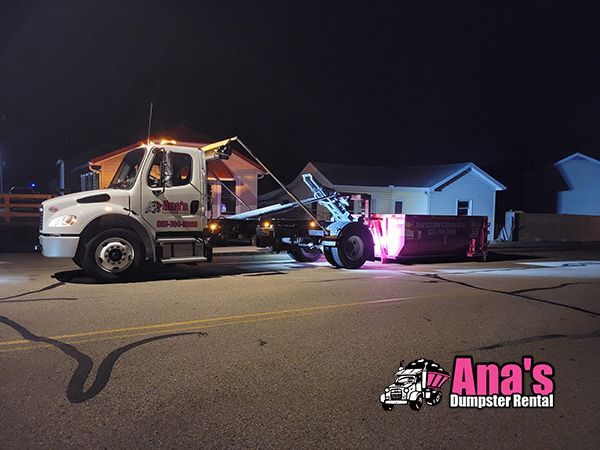 Tow truck loading a red car on a dimly lit street at night