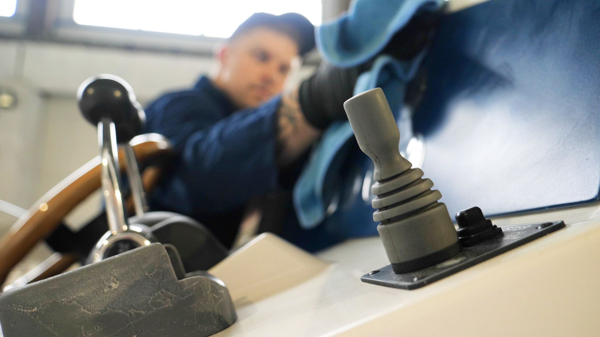 Close-up of a joystick and switch on a control panel with a blurred person in the background
