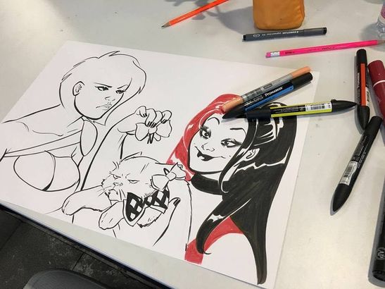 Due schizzi di personaggi in stile anime su carta, realizzati con pennarelli neri e rossi su una scrivania.