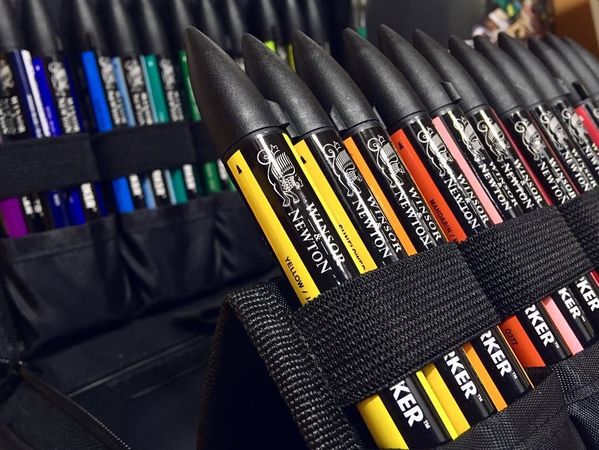 Primo piano di pennarelli neri con etichette colorate in un astuccio di tessuto