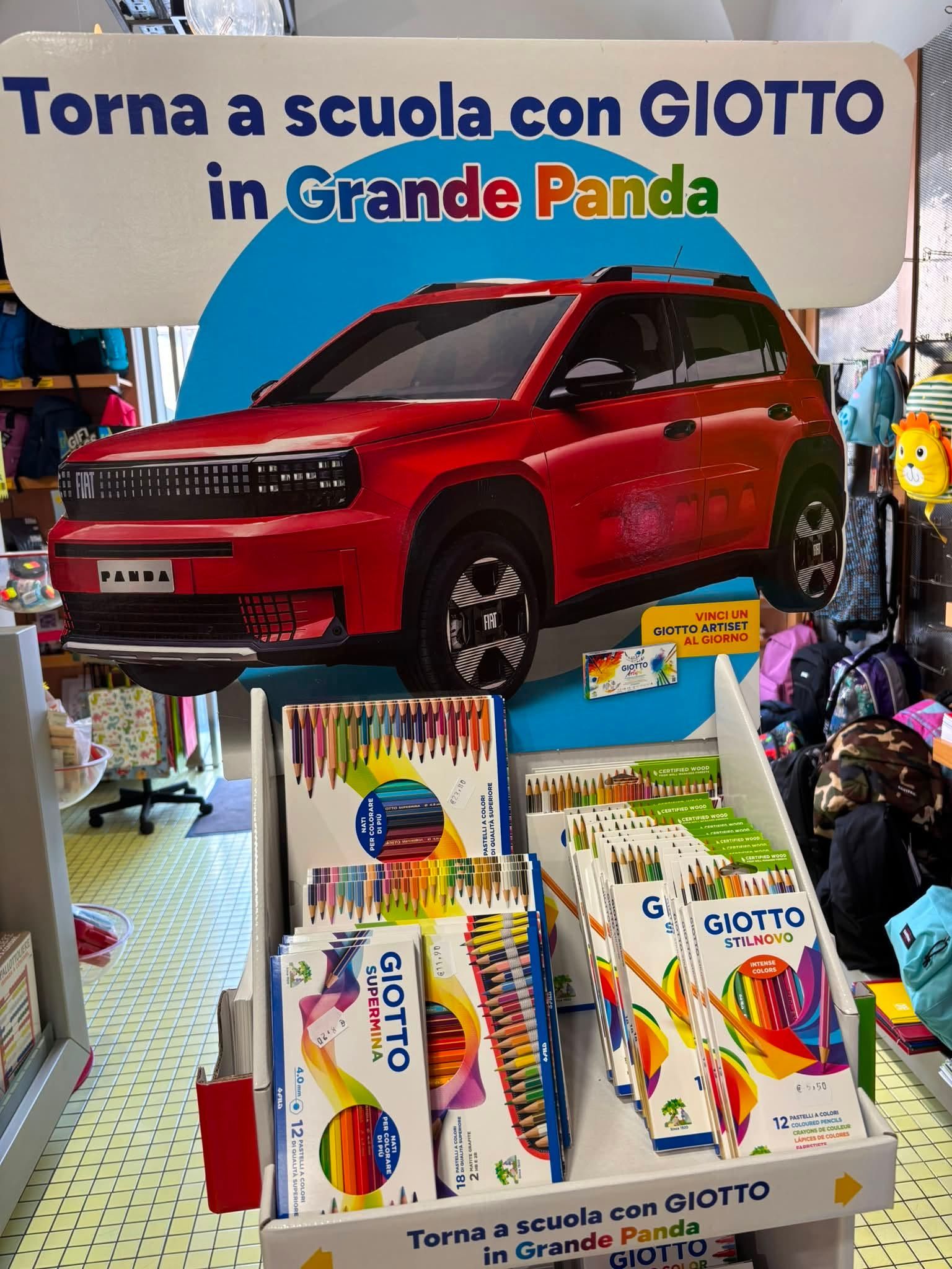 SUV giocattolo rosso in esposizione con materiale scolastico GIOTTO e striscione con la scritta “Torna a scuola con GIOTTO in Grande Panda”