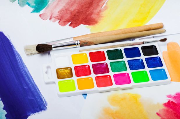 Tavolozza ad acquerello con colori vivaci, pennelli e pennellate brillanti su carta.
