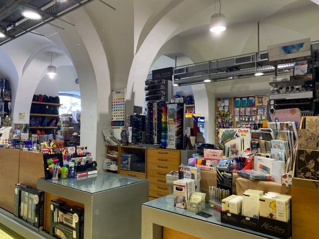 Interno di un negozio con soffitti a volta, scaffali con prodotti confezionati e banconi che espongono i prodotti.