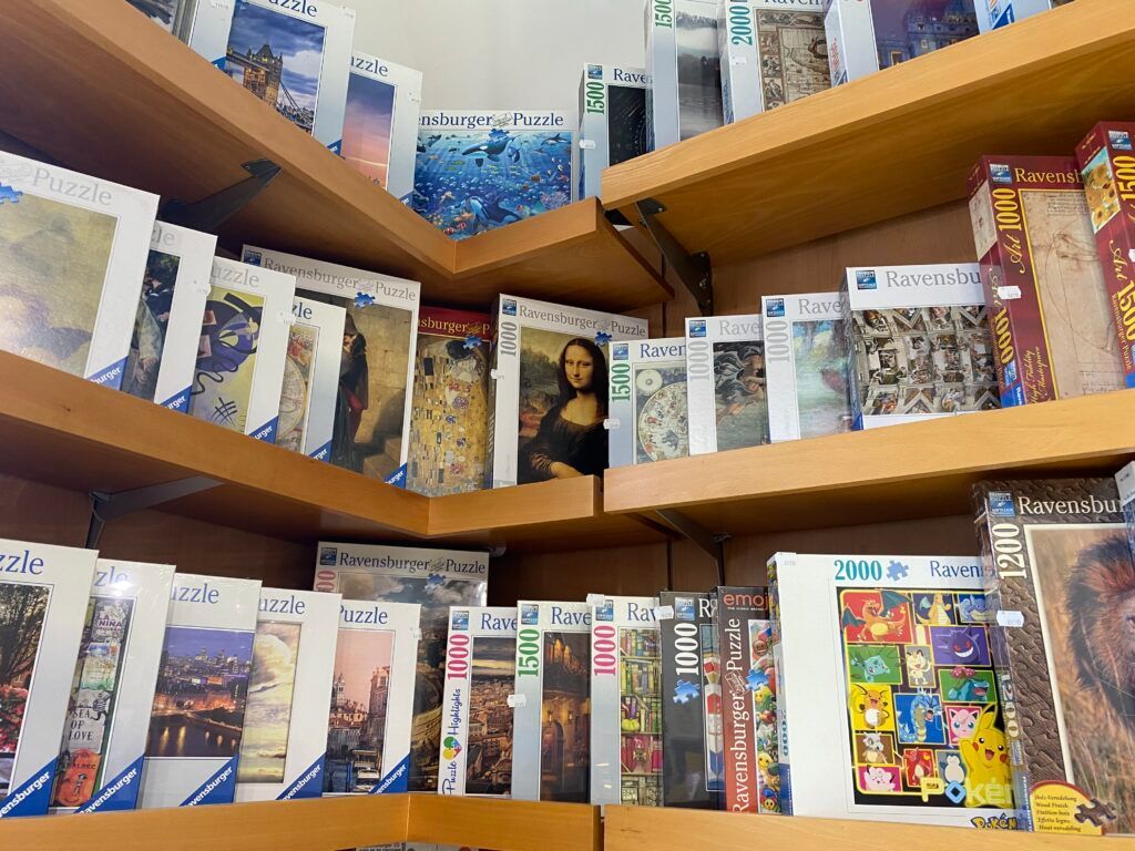 Libri e articoli in scatola disposti su scaffali di legno in una corsia di un negozio.
