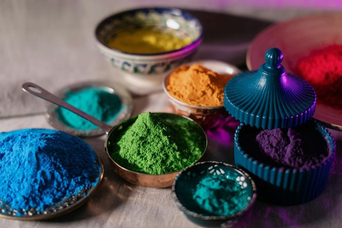 Ciotole di vivaci pigmenti in polvere nei colori blu, verde, viola e oro su un tavolo