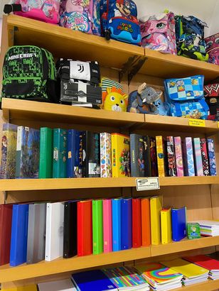 Libreria colorata per bambini con libri, giocattoli e zaini disposti su ripiani di legno.