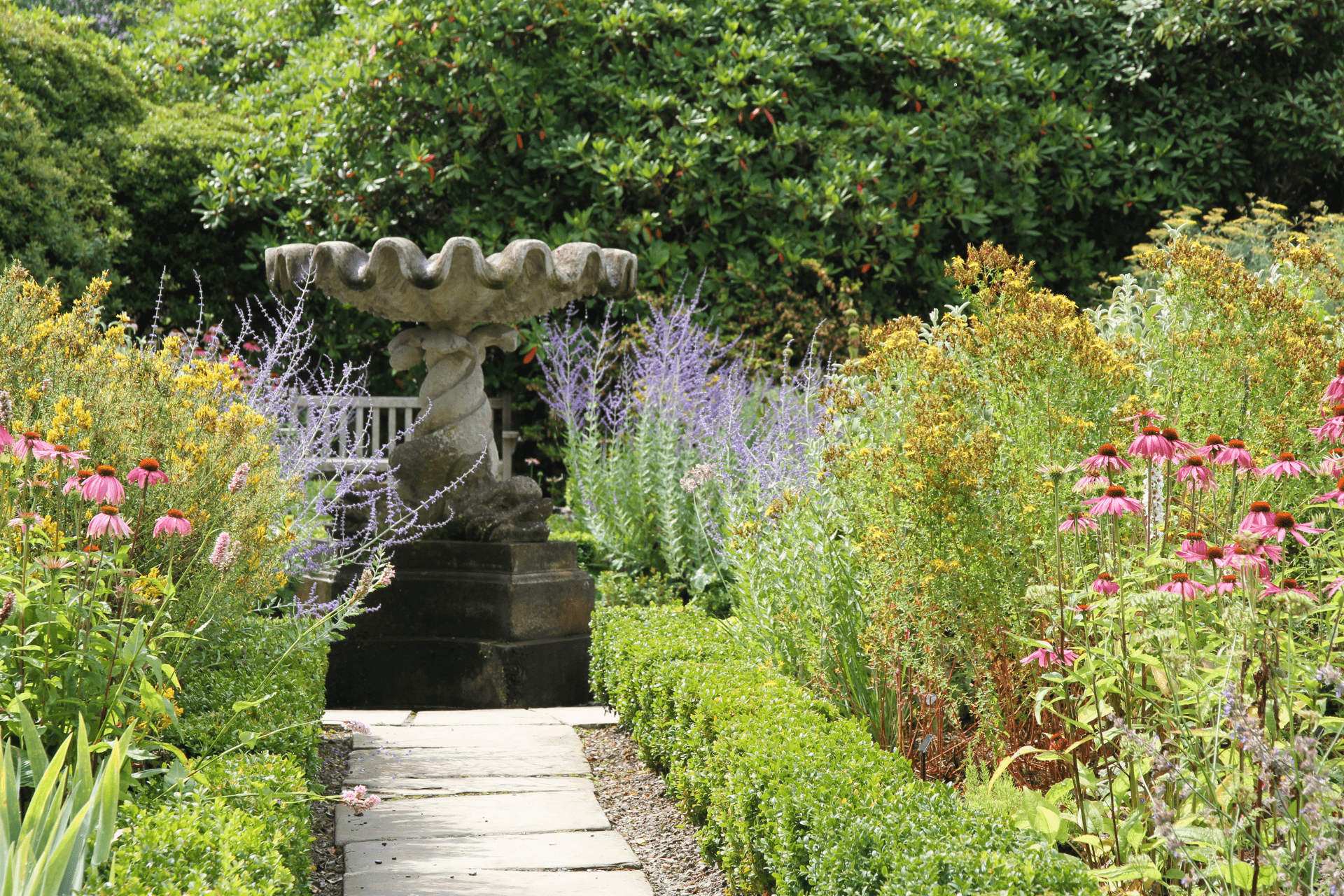 A birdbath at the end of the path in a garden