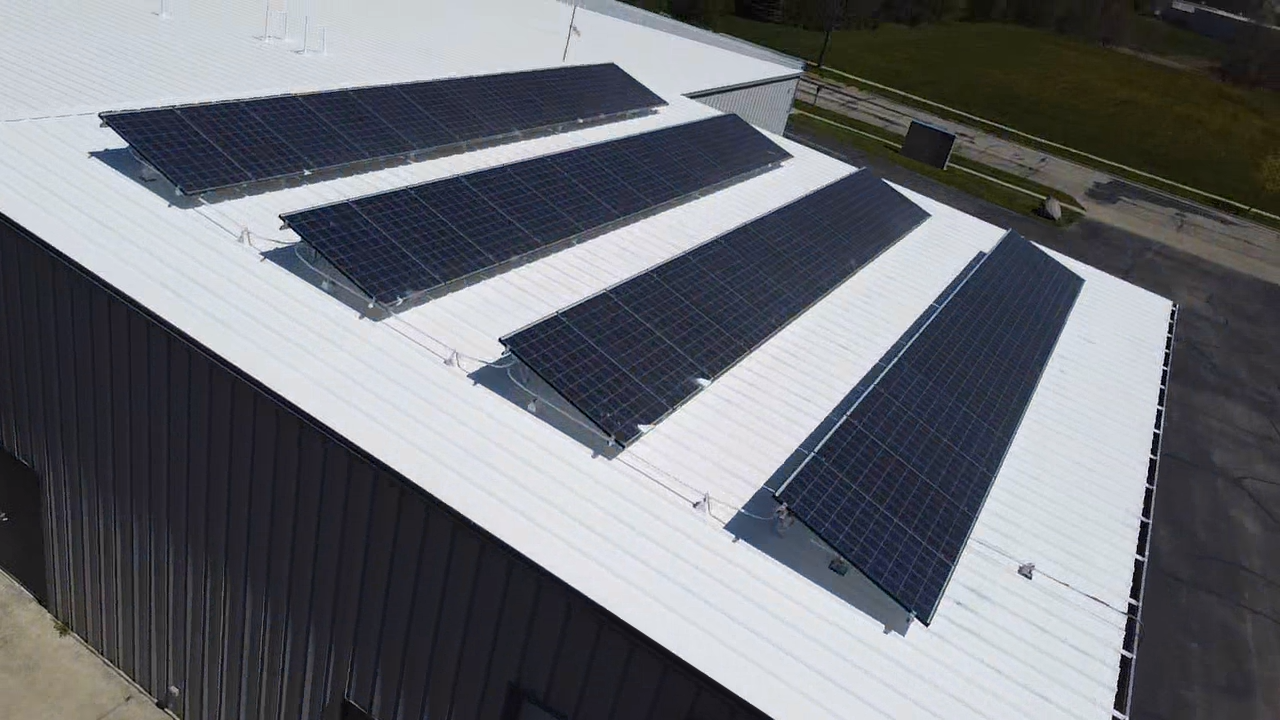 Solar panels on a white commercial building roof. Black panels angled towards the sun.