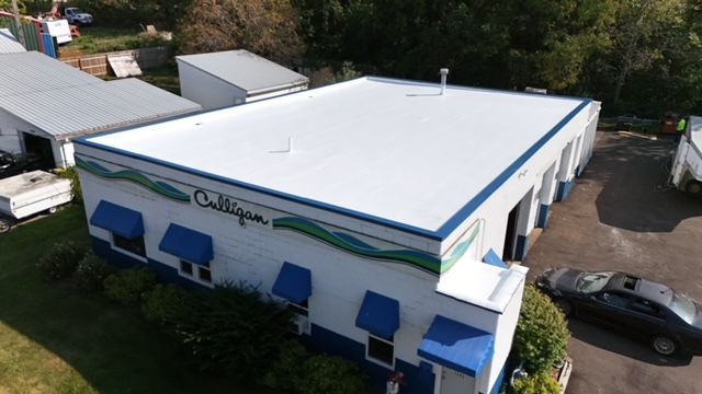 An aerial view of a building with a white roof and blue awnings.