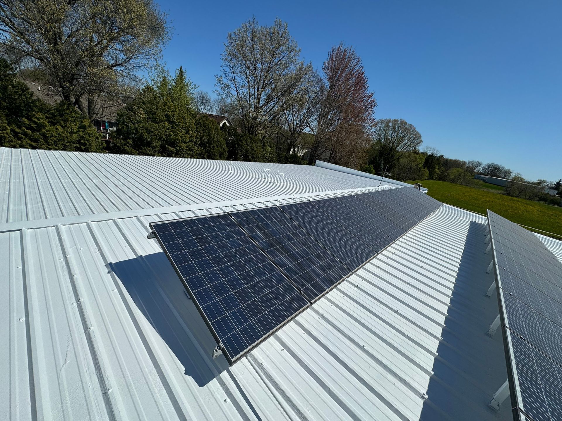 Solar panels on a bright, white metal roof on a sunny day.