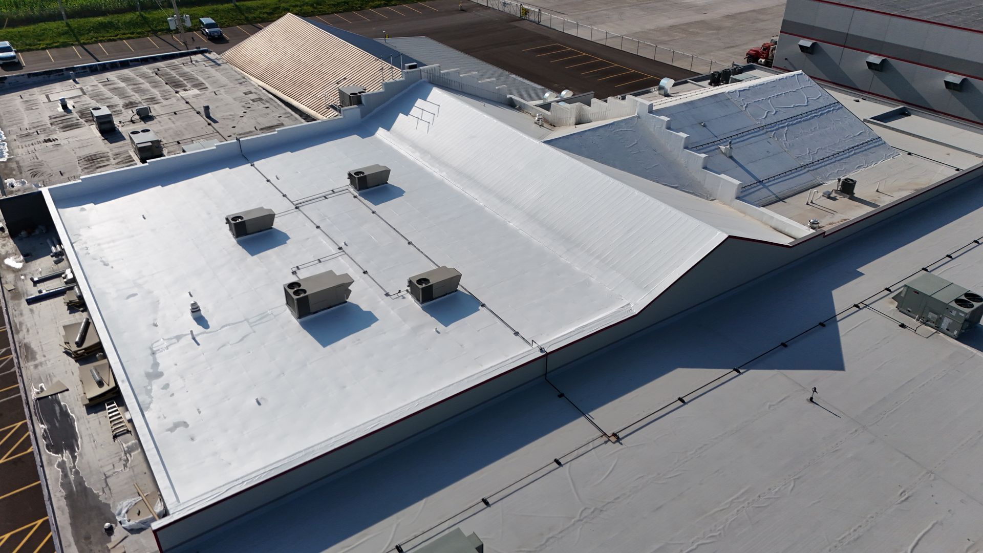 Aerial view of a commercial building's flat, silver roof with multiple HVAC units.