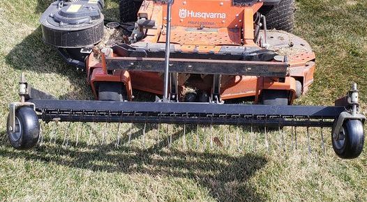 an orange riding lawn mower running along a large residential yard