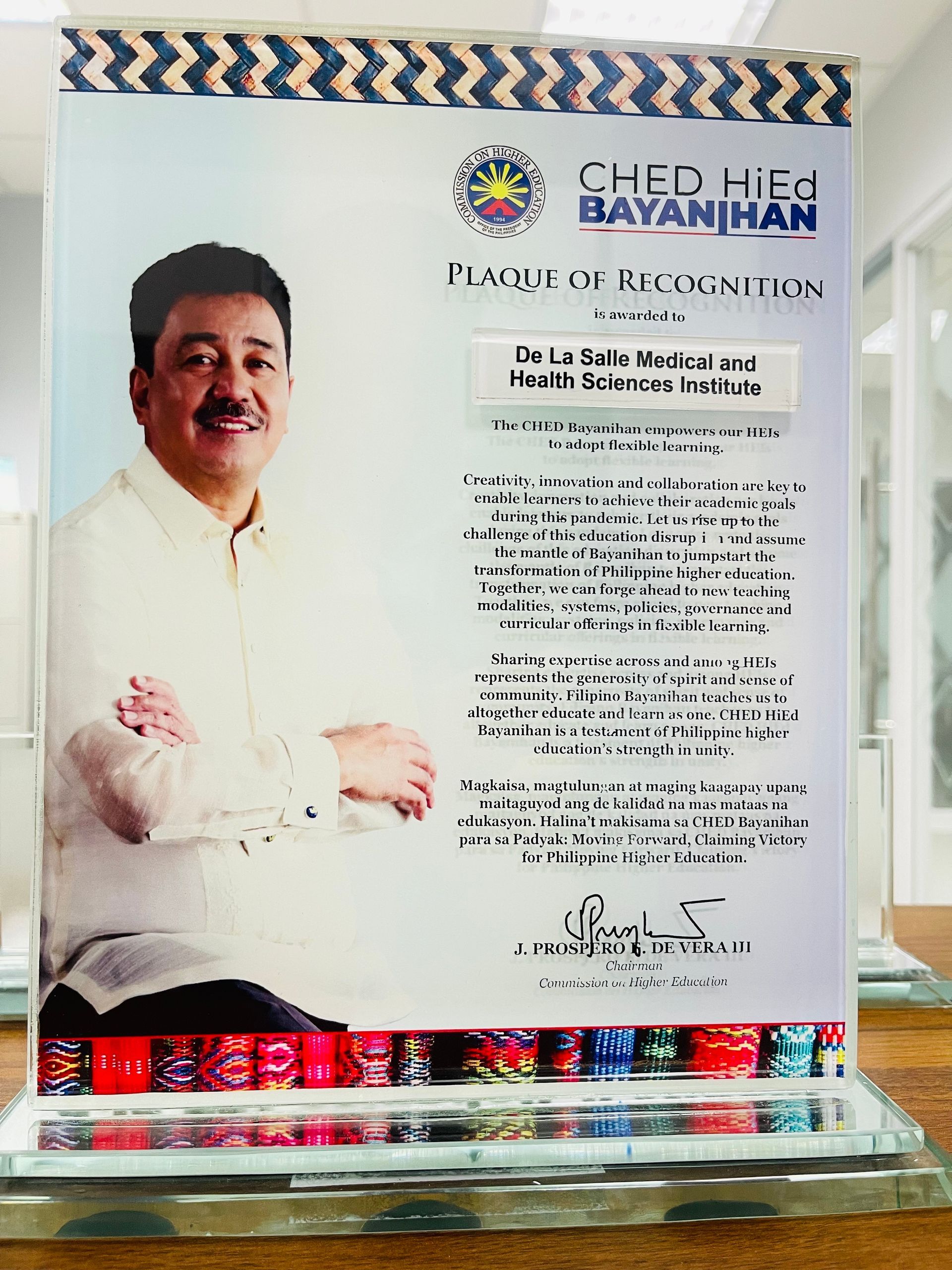 Plaque with portrait of a man beside a “Bayanihan” award certificate in a clear display case