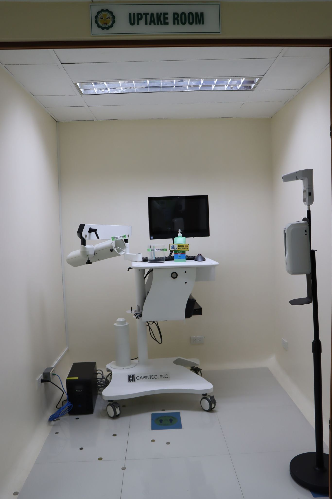 Empty medical procedure room with exam table, monitor, and equipment on white floor and walls