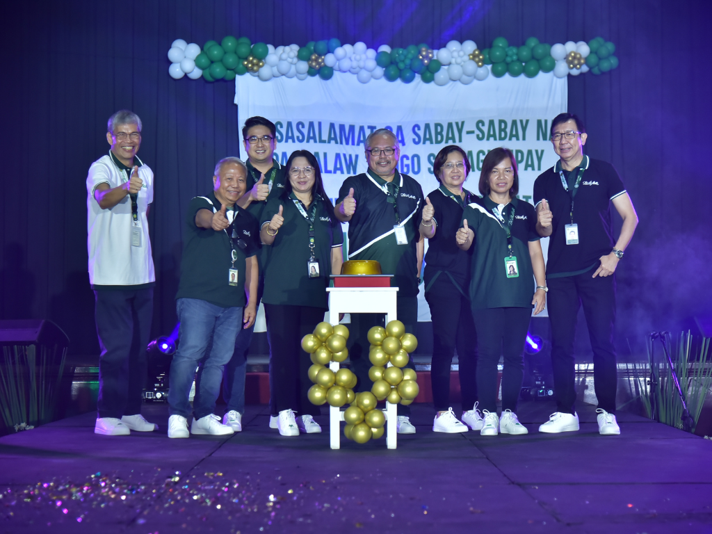 Group of people on a decorated stage posing with medals and trophies during an awards celebration
