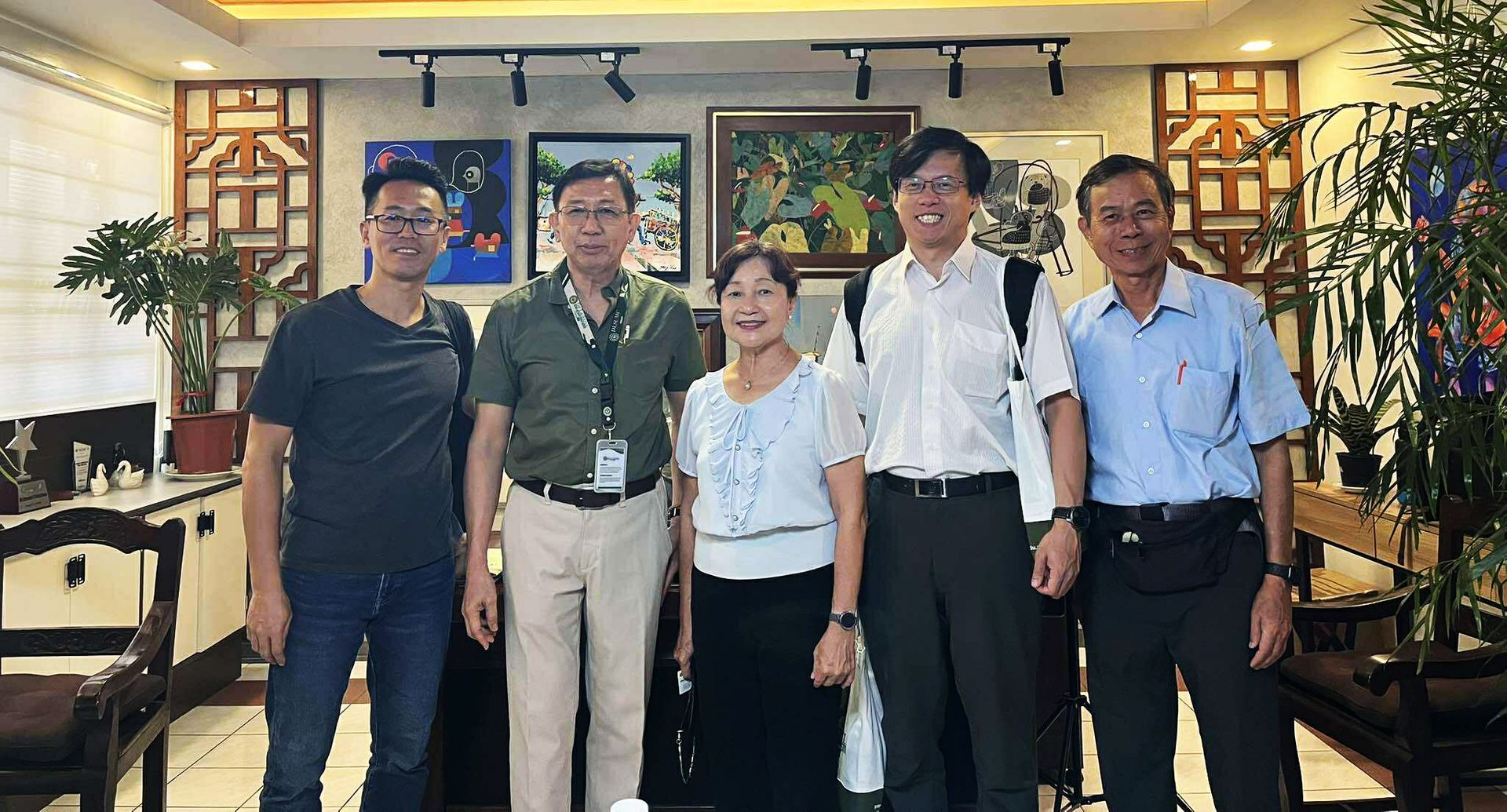 Five people standing together in a warmly lit indoor room, posing for a photo.