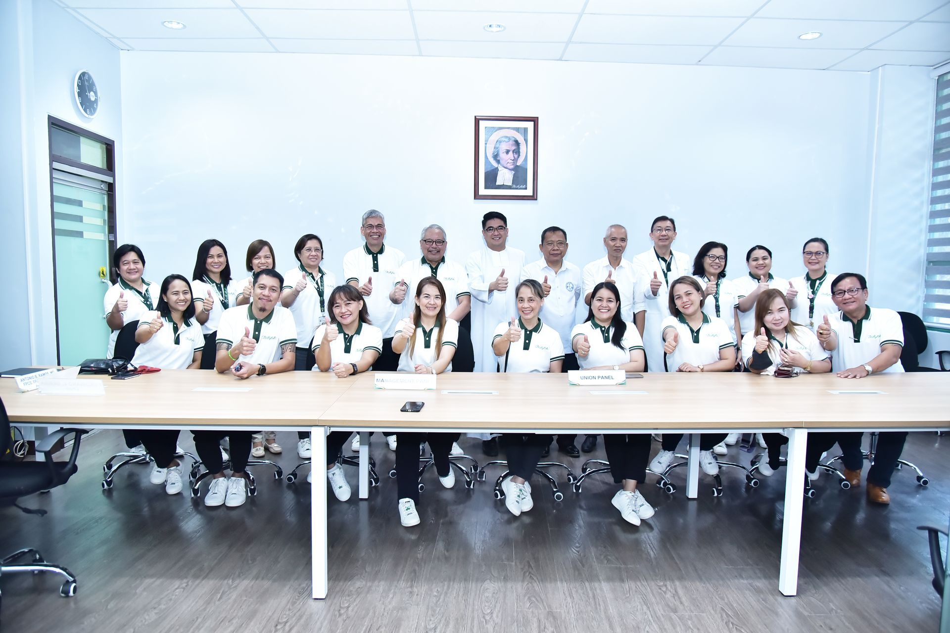 Group of people in white coats seated around a conference table in a bright meeting room