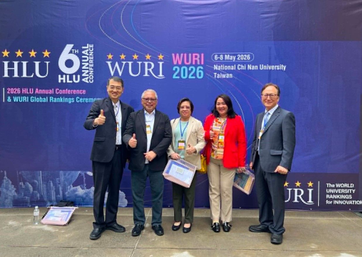 Five people posing at the HLU WURI 2026 event backdrop, holding certificates and smiling