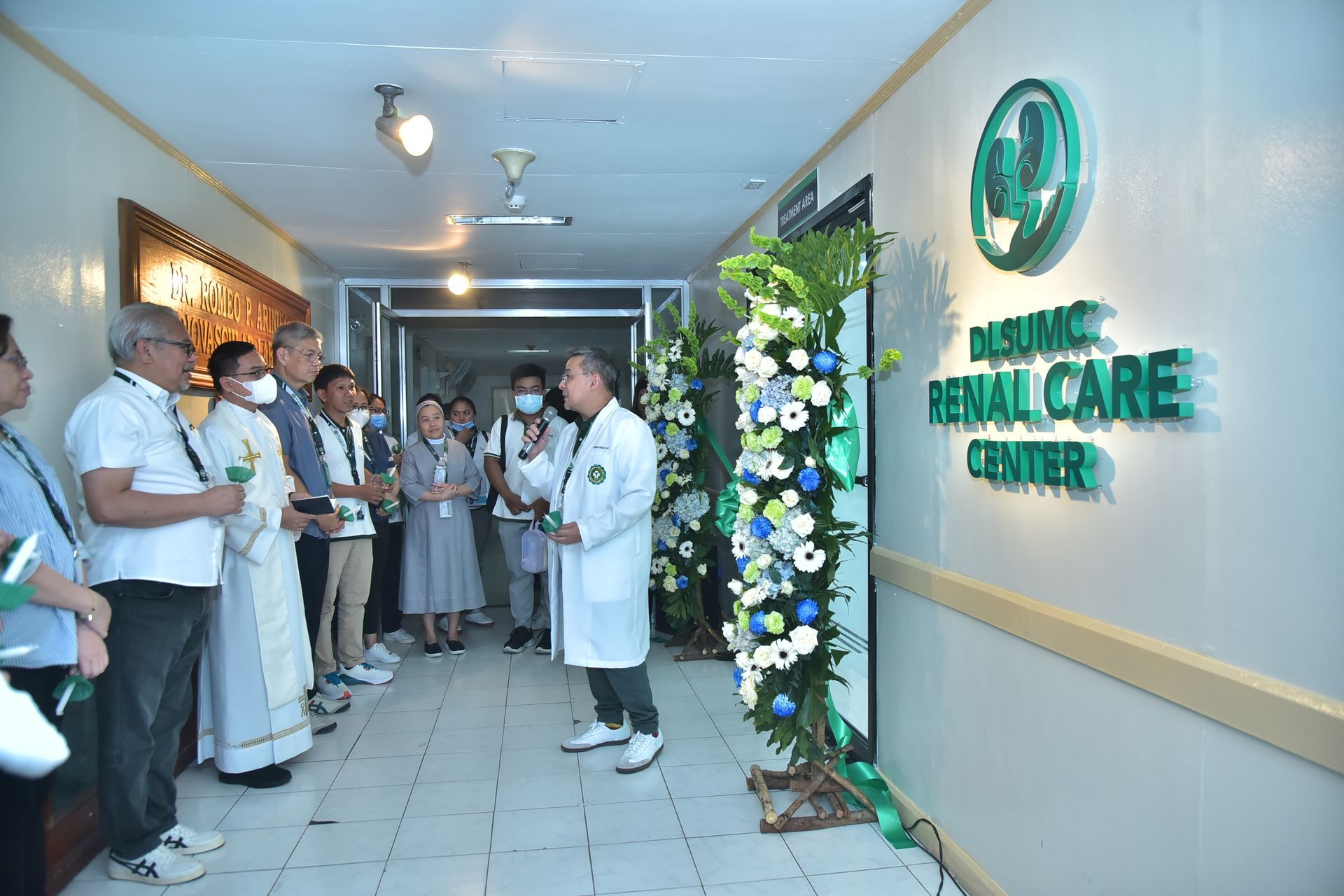 Doctors and staff gathered in a bright clinic hallway beside a green “Renal Care Centre” sign.