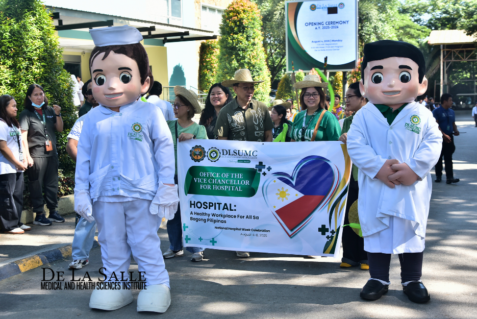Two oversized mascot figures flank a group holding a hospital banner outdoors.