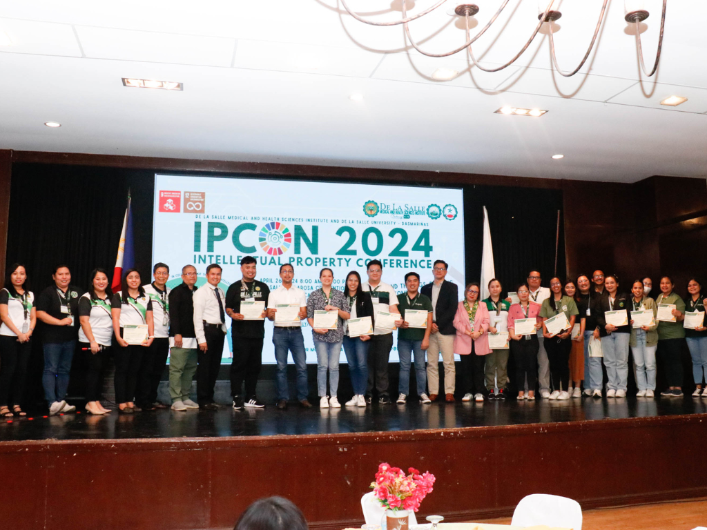 Group of people on a stage holding certificates at IPCN 2024 event banner