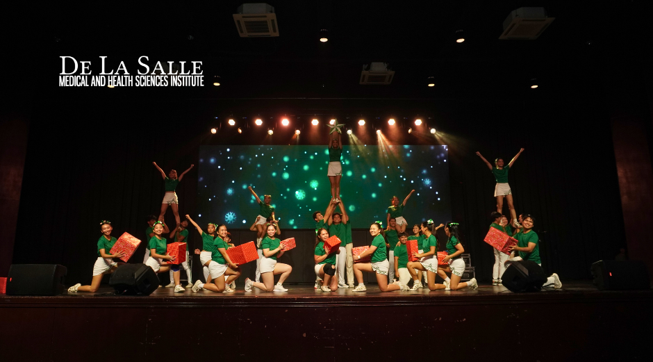 Students performing a colorful stage dance under warm lights at De La Salle school.
