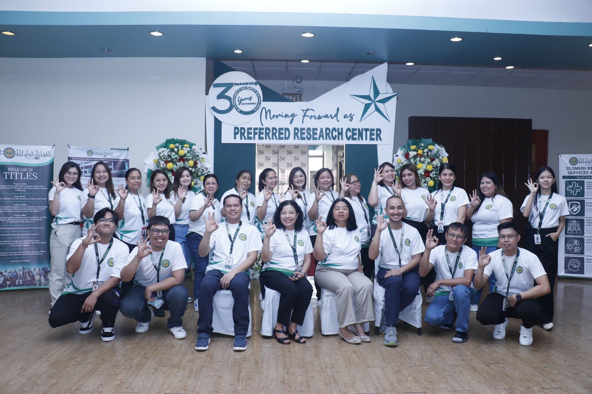 Group of people posing indoors in front of a “Preferred Beverage Center” banner, many wearing white shirts.
