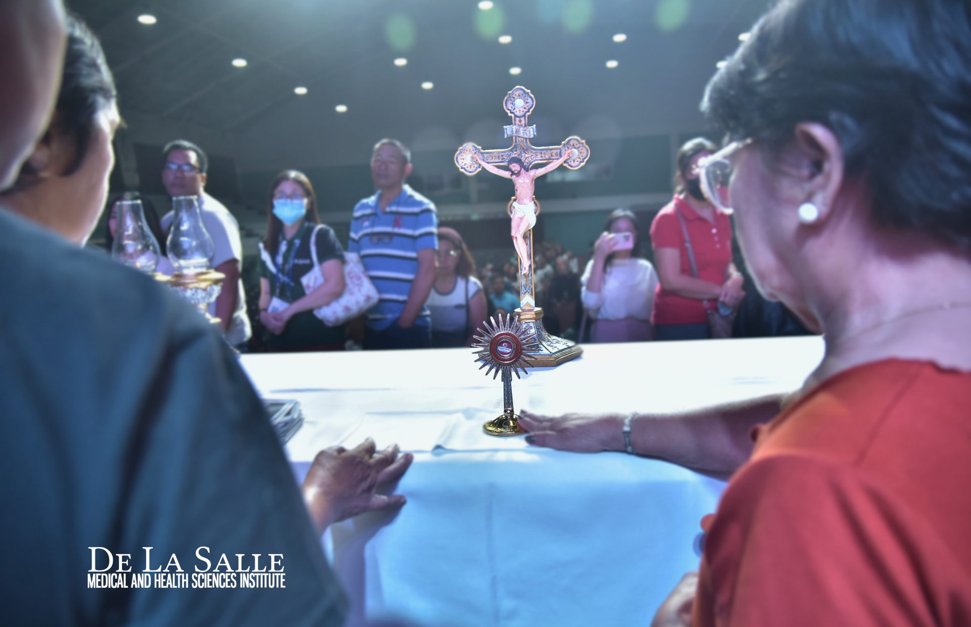 People gathered around a table with a crucifix at the center during a religious ceremony