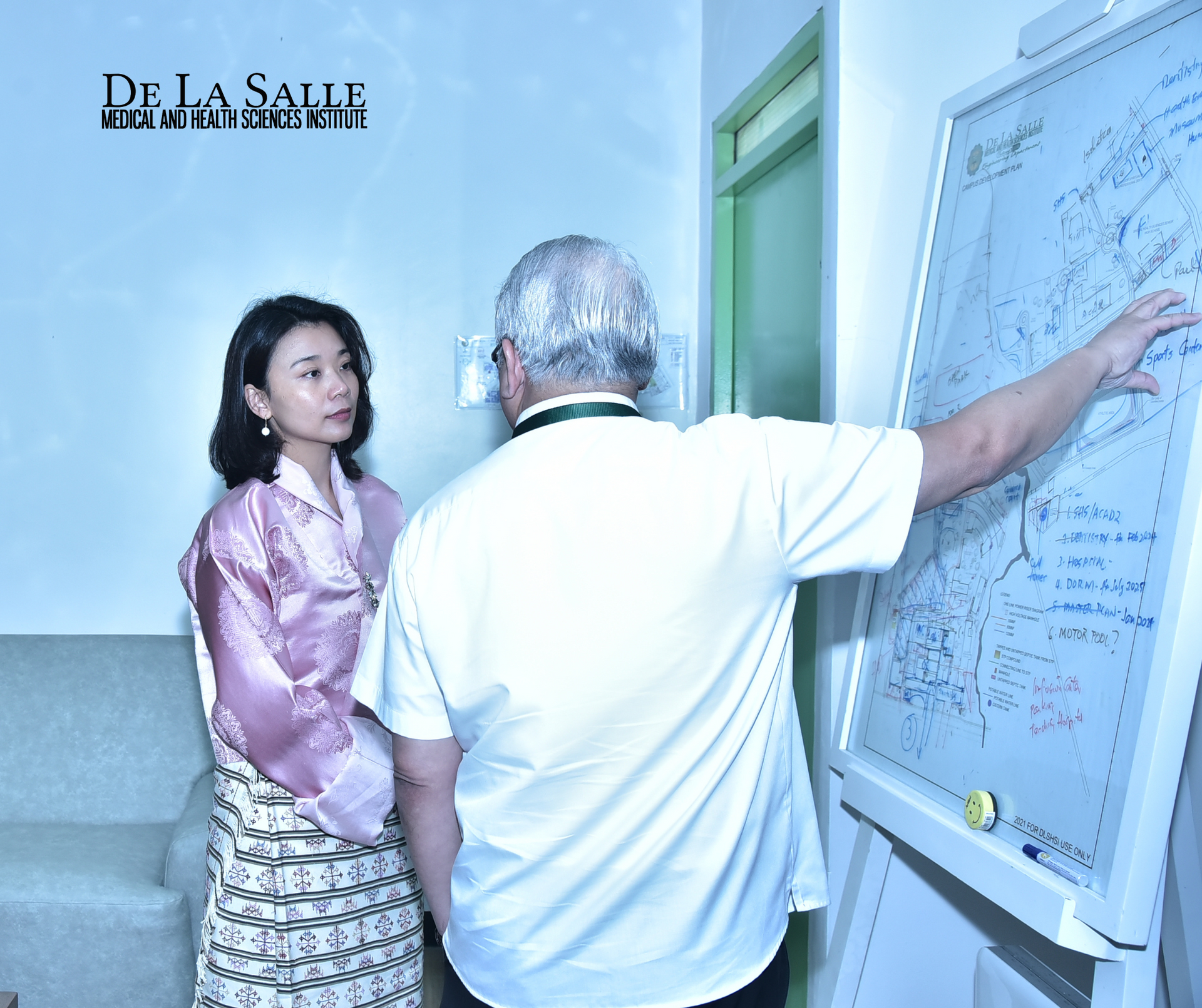 Two people discussing notes on a whiteboard in a classroom hallway