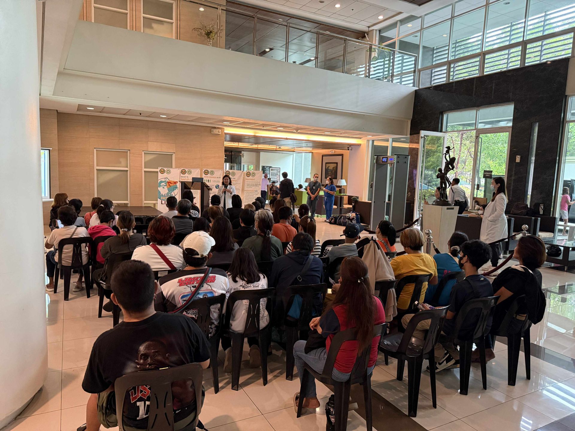 People seated in an indoor auditorium watching a presentation on stage.