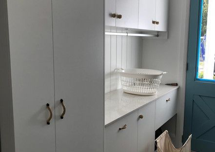 There is a laundry basket on the counter in the laundry room.