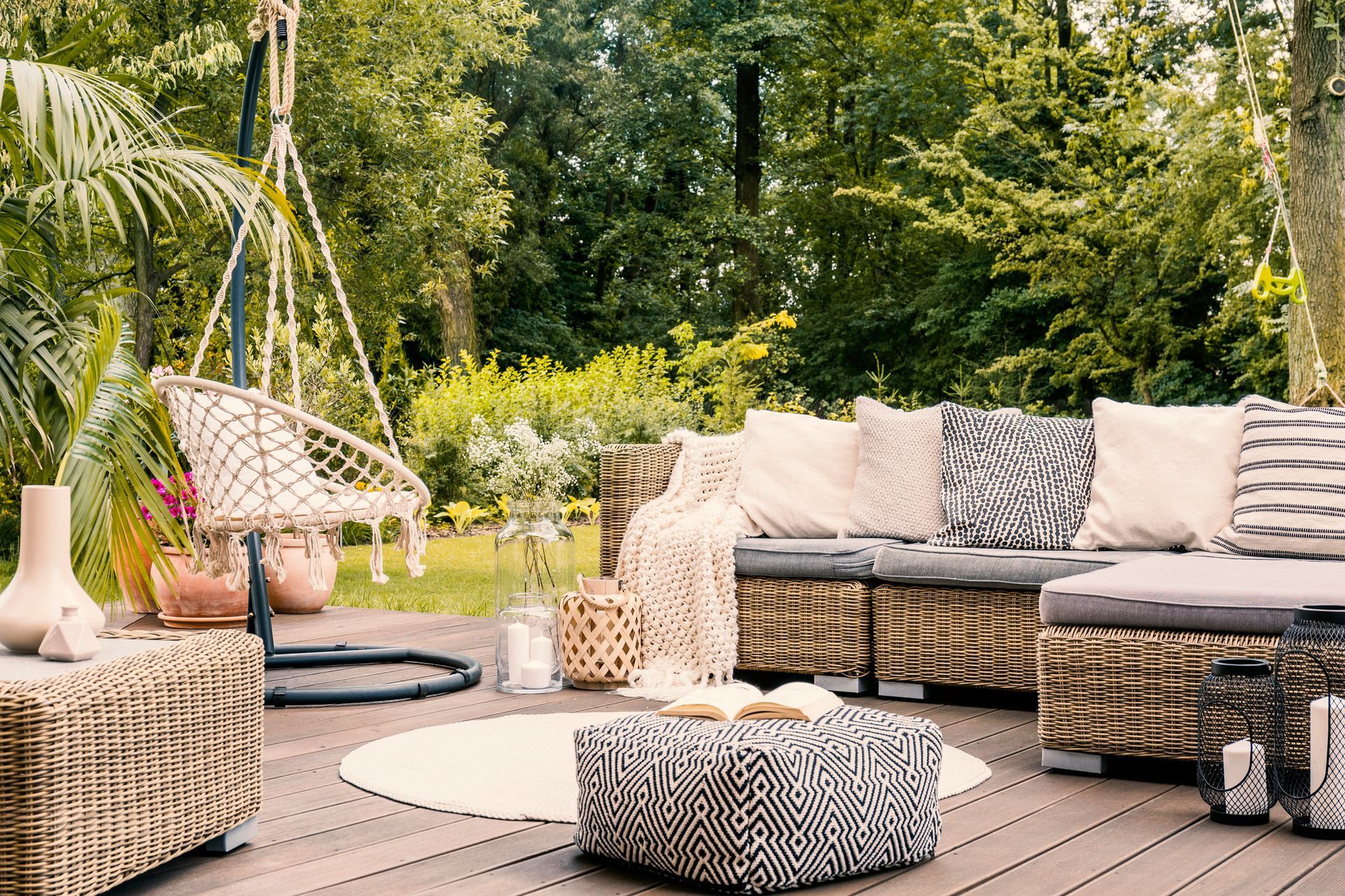 A wooden deck with wicker furniture and a hanging chair.