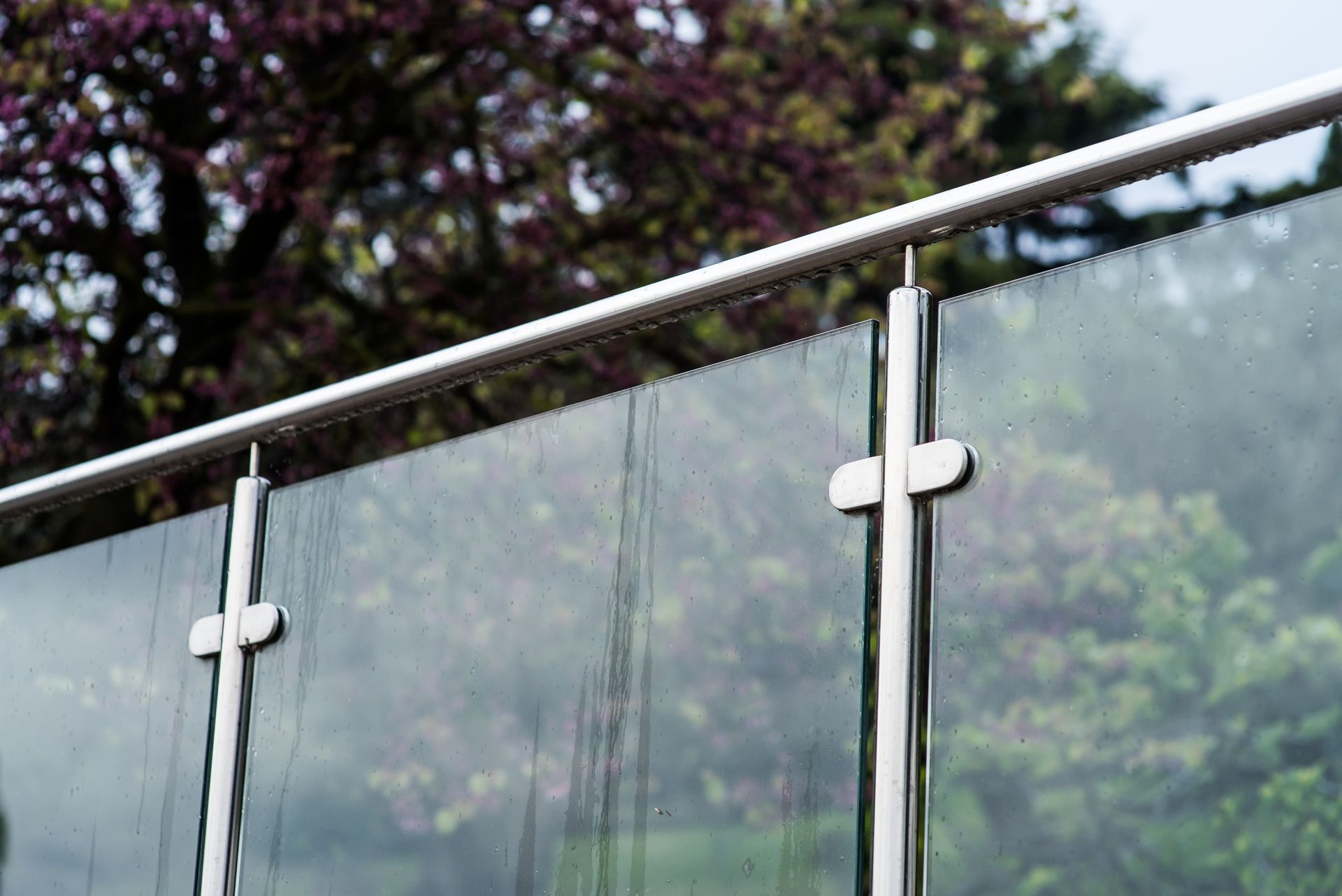 Glass And Steel Railing With A Blurred Tree Background — Soward Steel & Aluminium Fabrication in South Lismore, NSW
