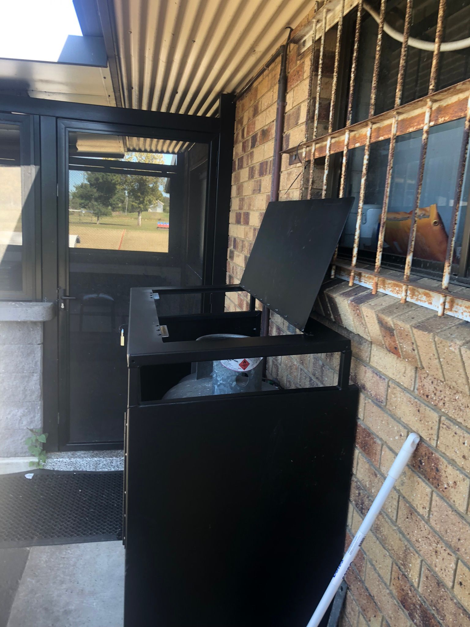 Black Metal Trash Bin With Open Lid Next To A Building Entrance — Soward Steel & Aluminium Fabrication in Byron Bay, NSW