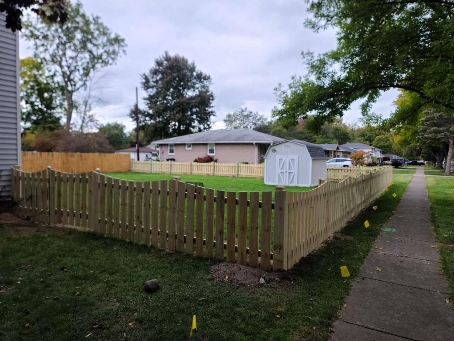 Skilled worker repairing the wooden fence around a house, using tools and materials to fix and reinforce the structure.
