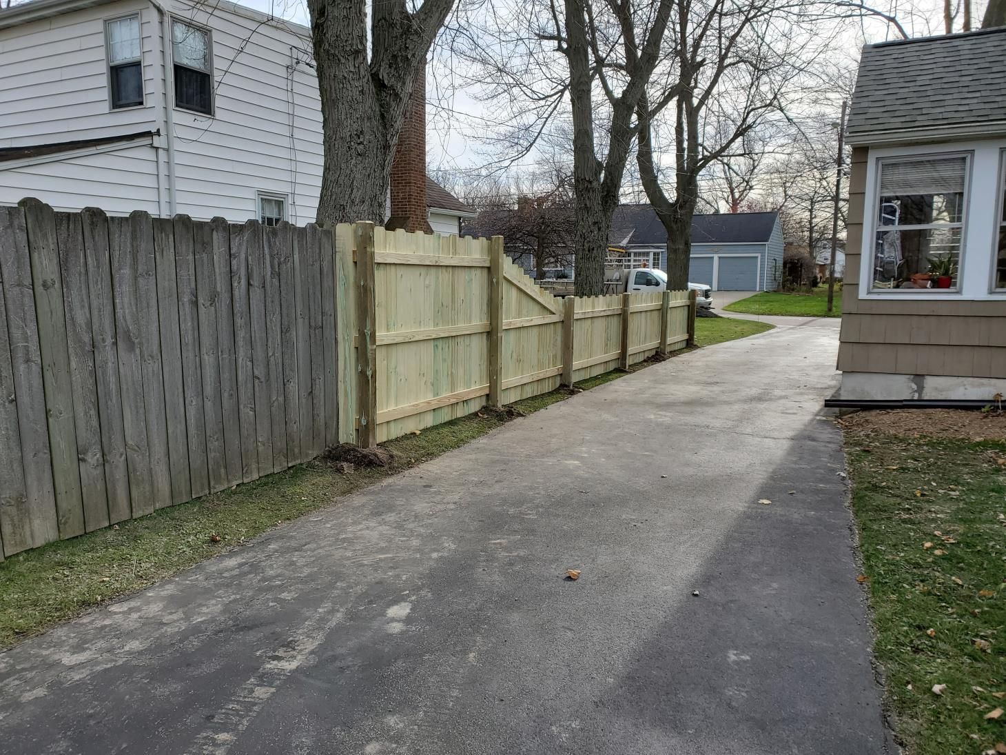 Person using a power tool to sand and polish an aging wooden fence, giving it a renewed appearance.