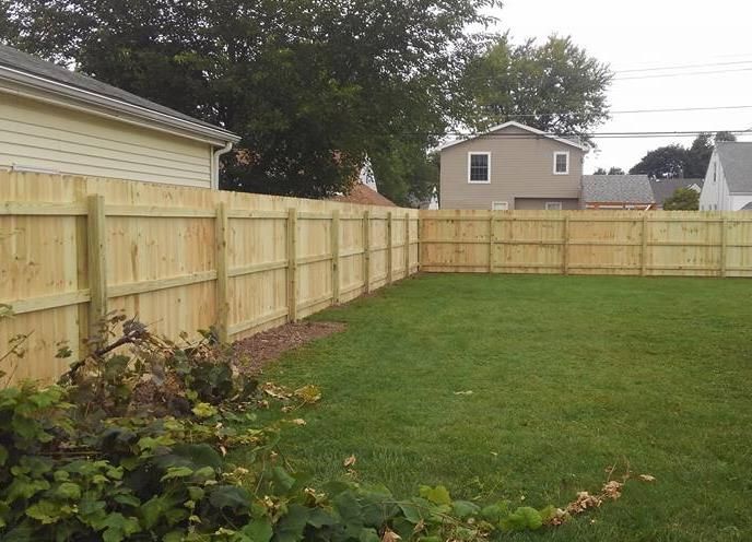 a person is using a drill on a green fence