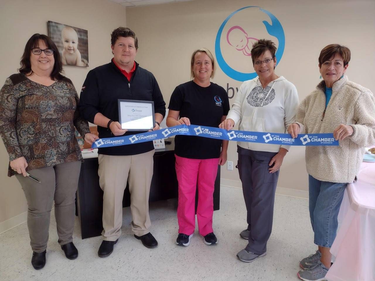 A group of people holding a blue ribbon that says baby